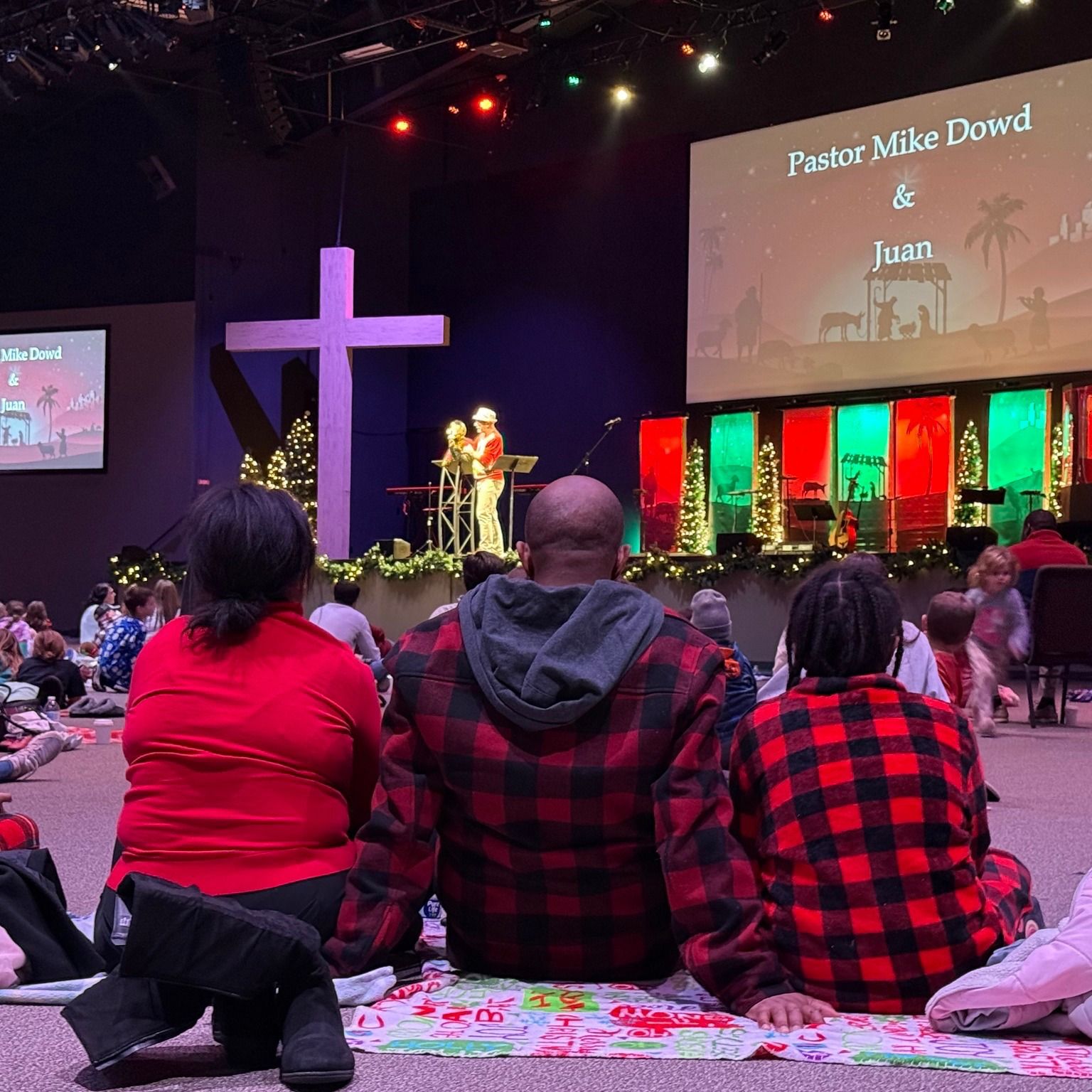 A group of people are sitting in front of a large screen that says pastor mike dowe