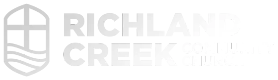 The logo for richland creek is gray and has a shield on it.