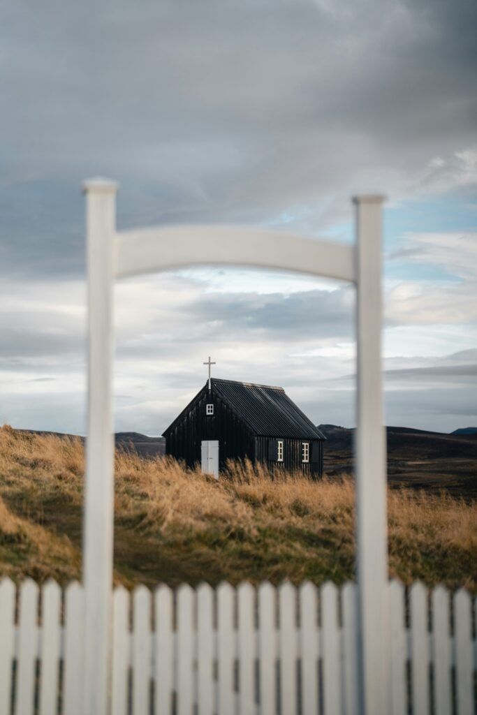 A black house is behind a white picket fence.
