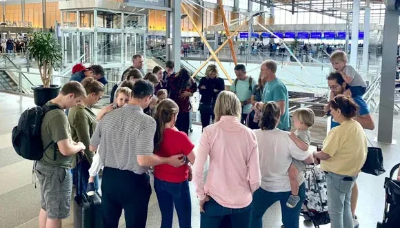 A group of people are standing in a circle at an airport.