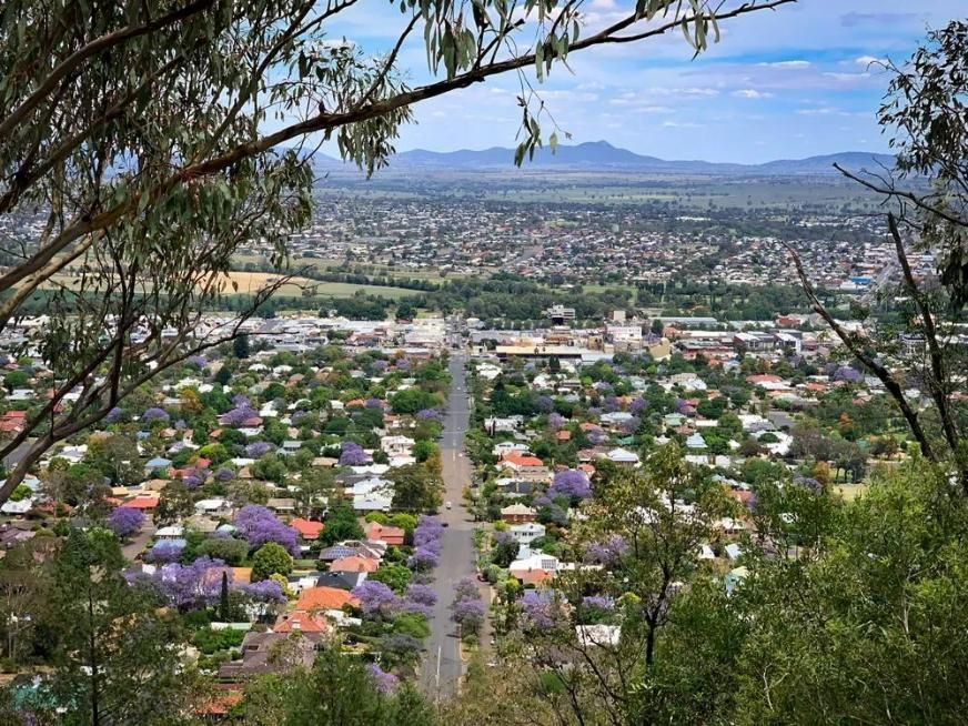 A View of A City from A Hill with Trees in The Foreground and Mountains in The Background — Trussted Frames & Trusses in Tamworth, NSW