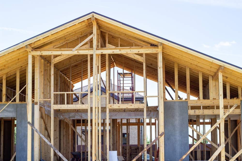 A House Is Being Built With Wooden Beams And A Roof — Trussted Frames & Trusses in Maitland, NSW