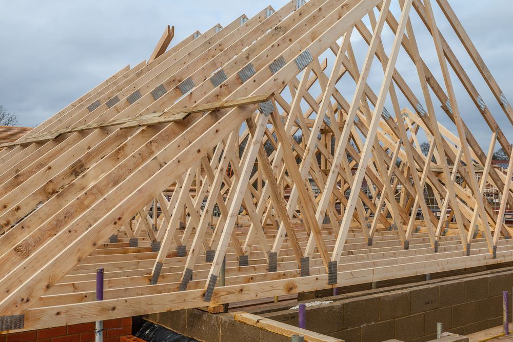 The Roof of A House Is Being Built with Wooden Beams — Trussted Frames & Trusses in Bennetts Green, NSW