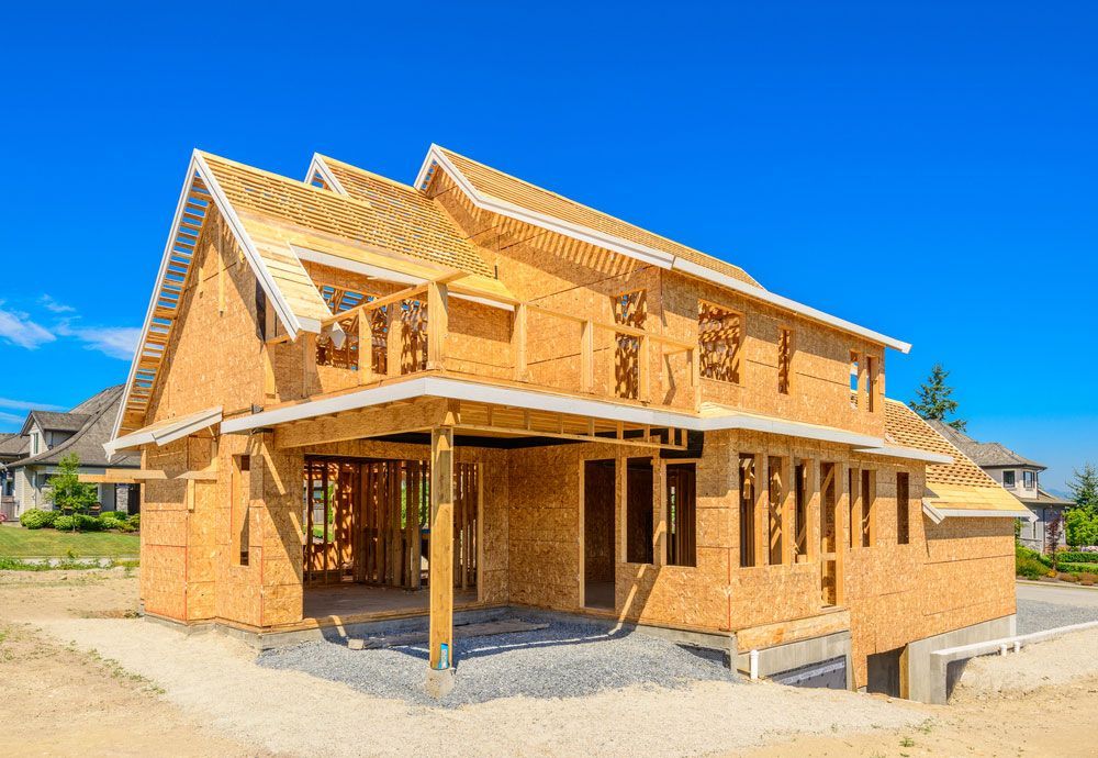 A Large Wooden House Is Being Built In A Residential Area — Trussted Frames & Trusses in Taree, NSW
