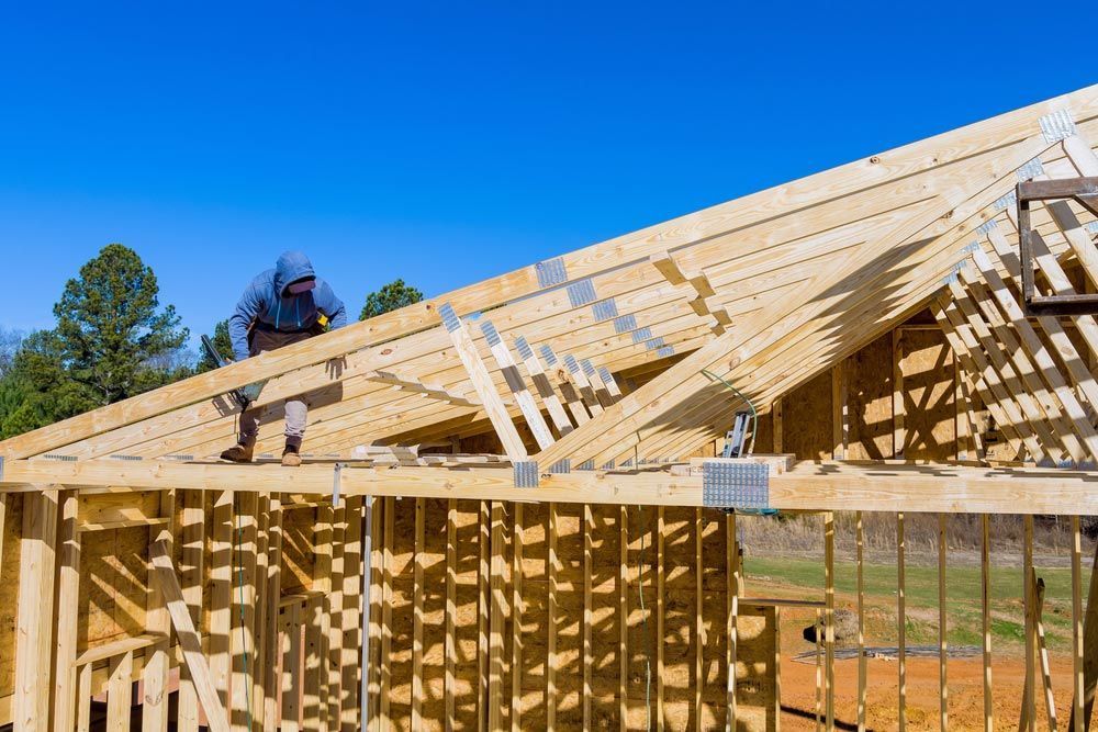 Standard Timber Framed Building With Close Up On The Roof Trusses Workers Nailing Wood Beams — Trussted Frames & Trusses in Port Macquarie, NSW