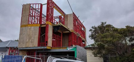 A Building Is Being Built on A Cloudy Day with A Truck Parked in Front of It — Trussted Frames & Trusses in Bennetts Green, NSW