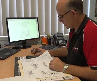 A Man Is Sitting at A Desk in Front of A Computer — Trussted Frames & Trusses in Bennetts Green, NSW