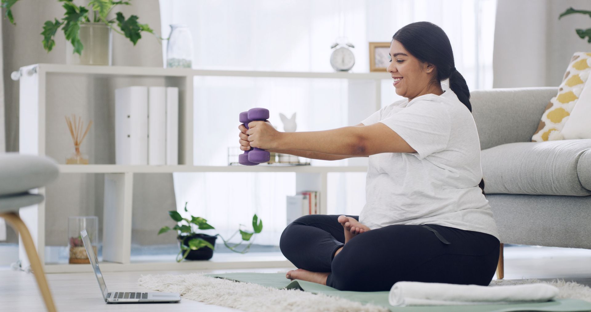 Woman doing seated stretches on a yoga mat in a bright living room