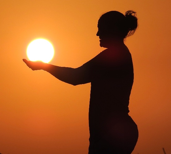 A silhouette of a woman holding the sun in her hands