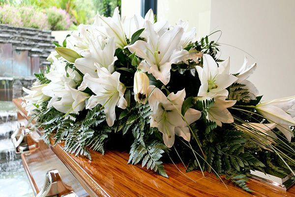 a wooden coffin with a bouquet of white flowers on it .