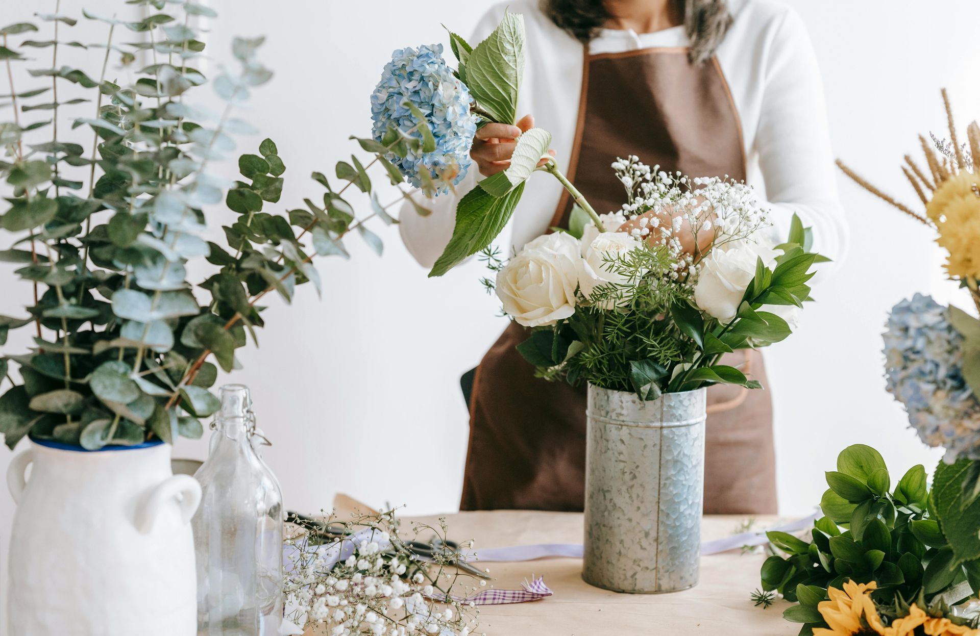 a woman is arranging flowers in a vase on a table .