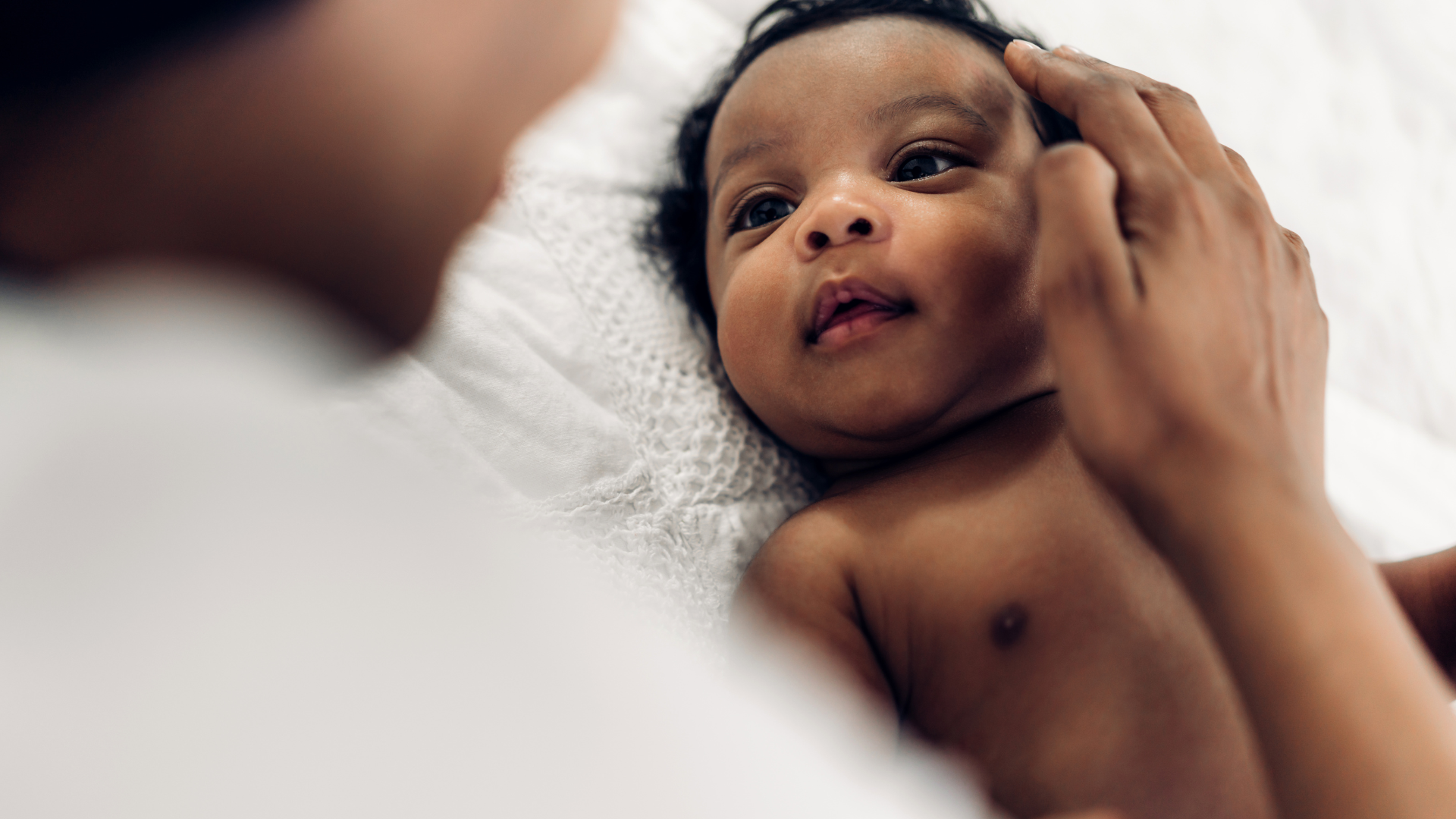 A woman is holding a baby in her arms and touching its face.