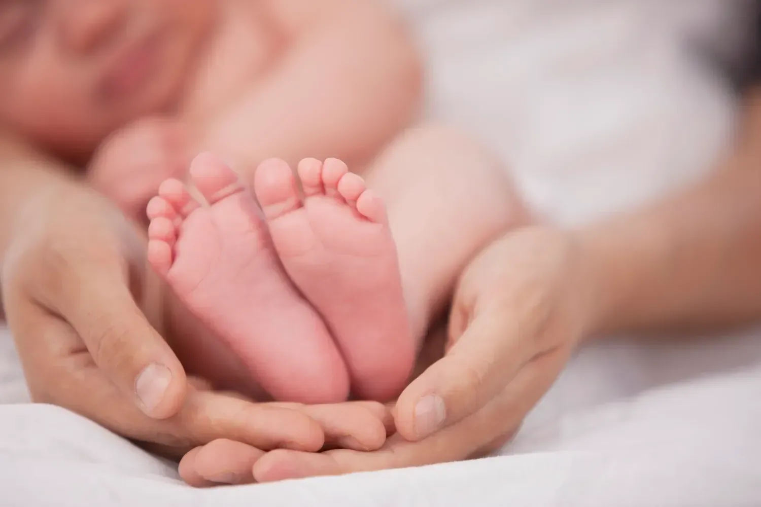 A person is holding a baby 's feet in their hands.