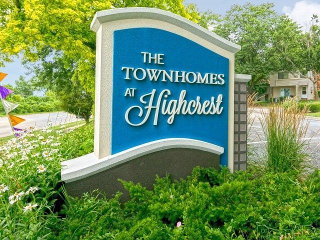 The Townhomes at Highcrest sign amid green landscaping and trees