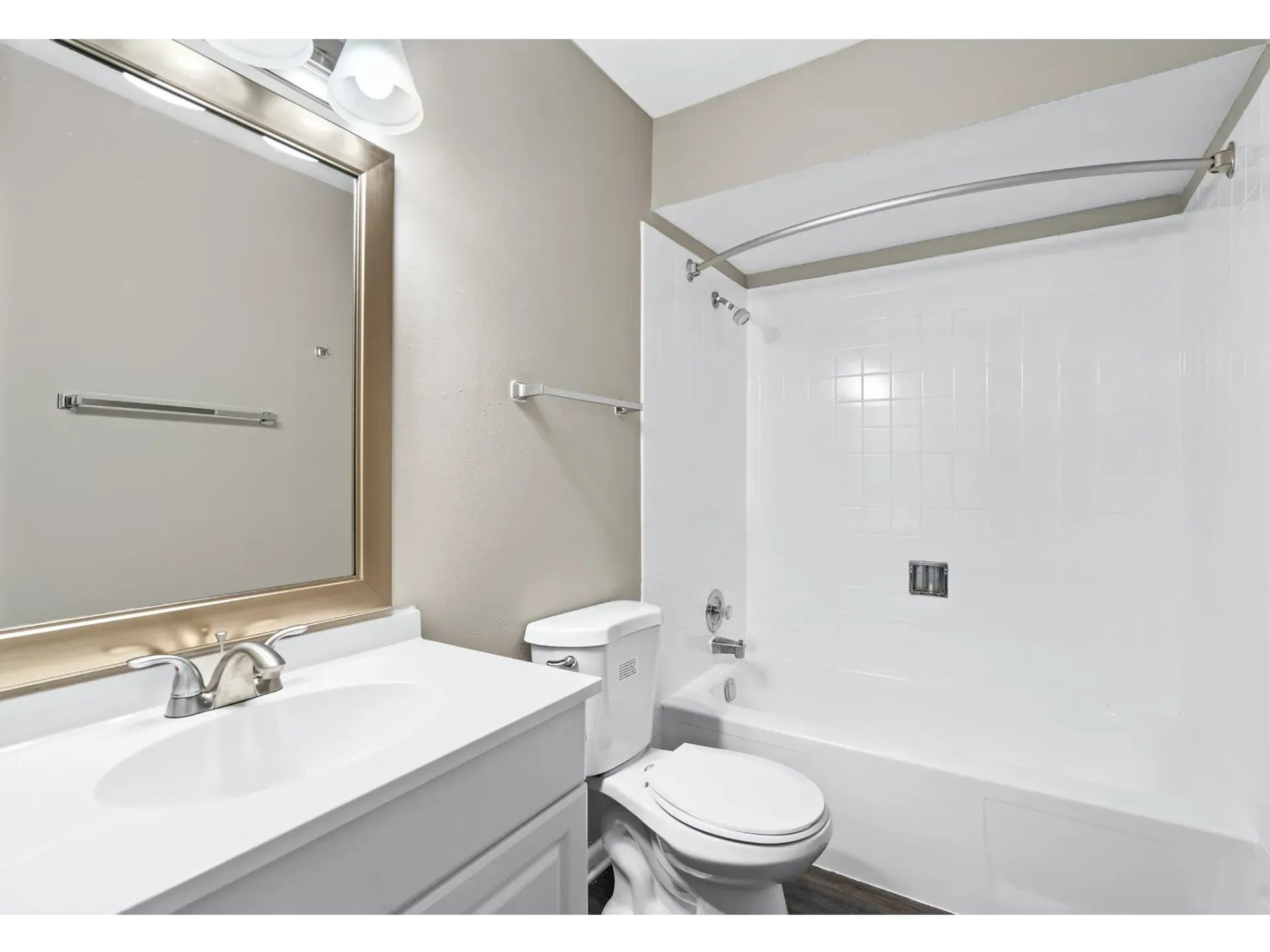 A modern bathroom featuring a bathtub, toilet, and sink with a large mirror.