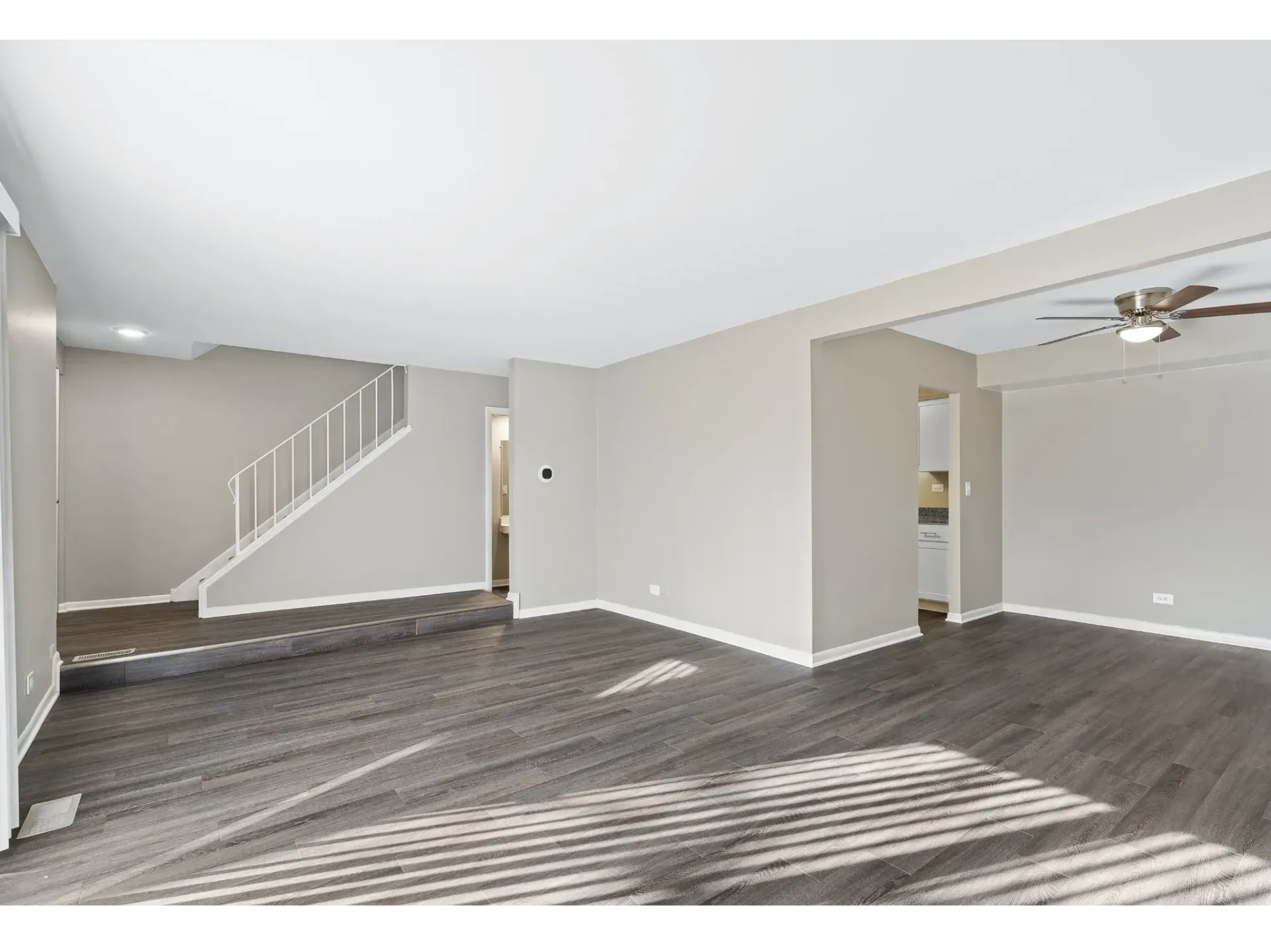 Spacious living area with hardwood flooring and a staircase