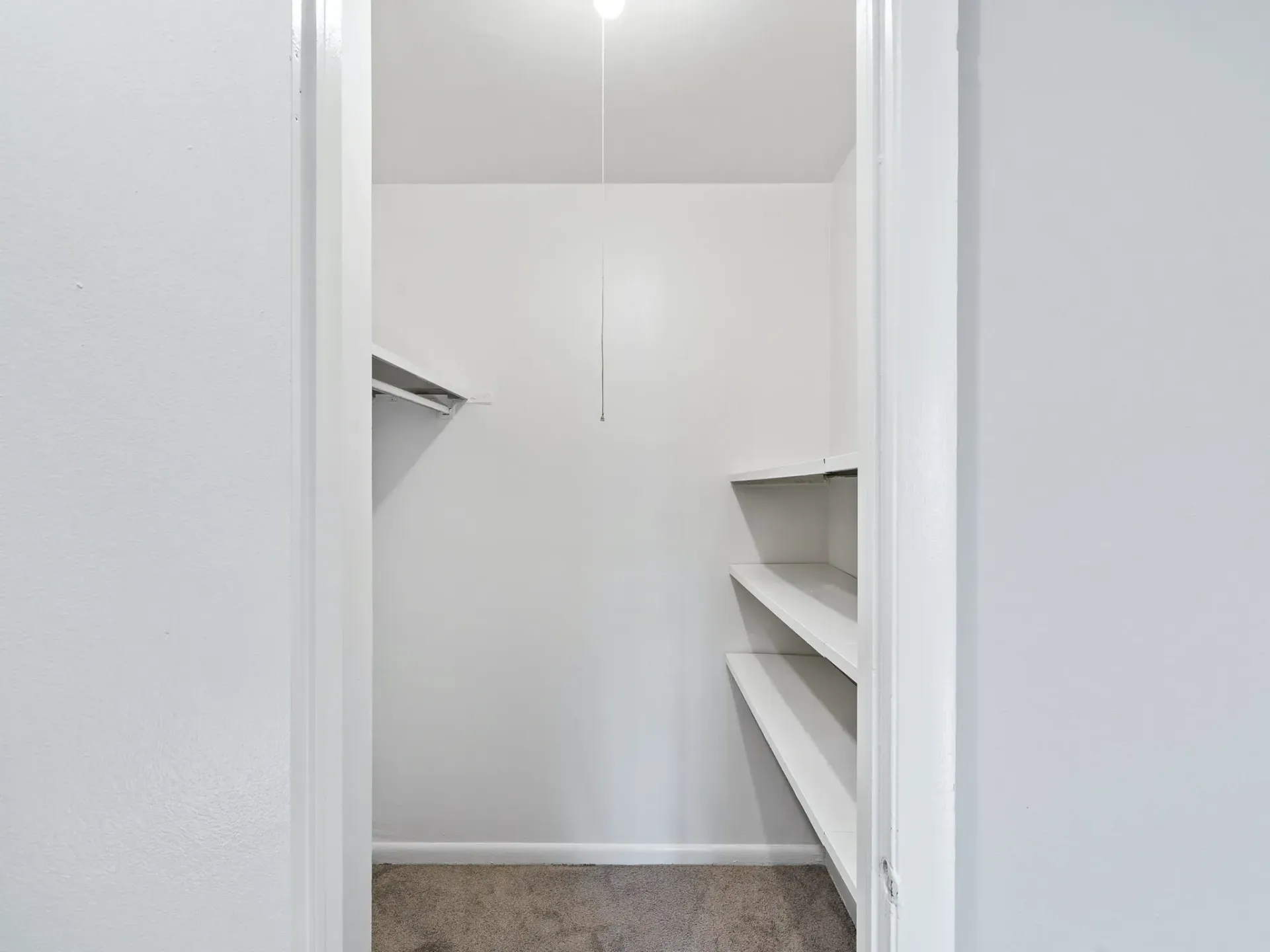 Inside view of a spacious closet with white shelves