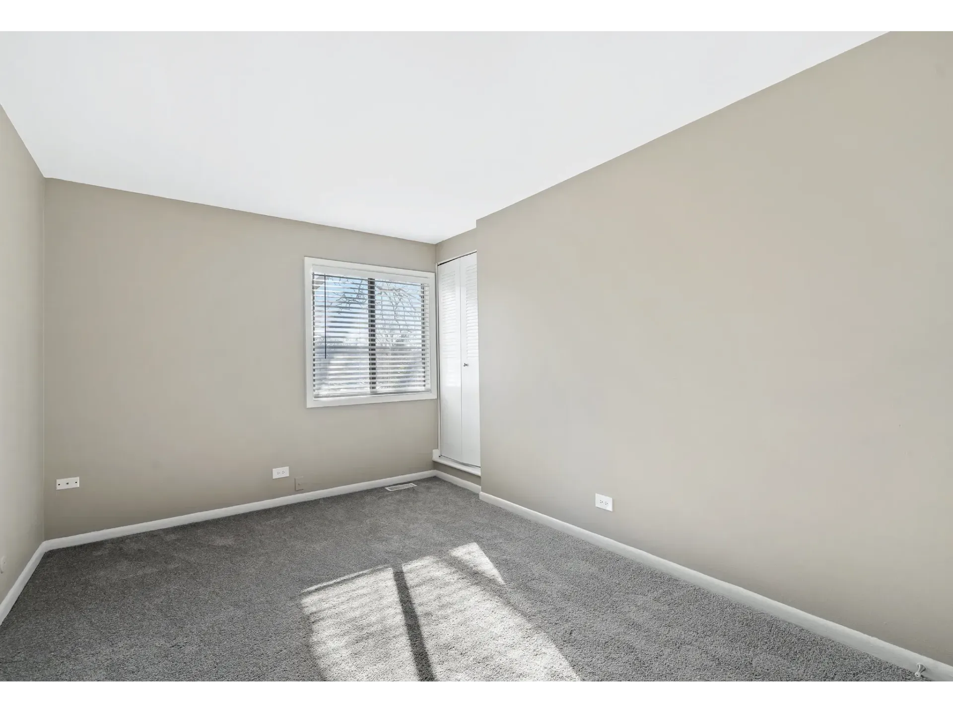 Empty apartment room with gray carpet and a window