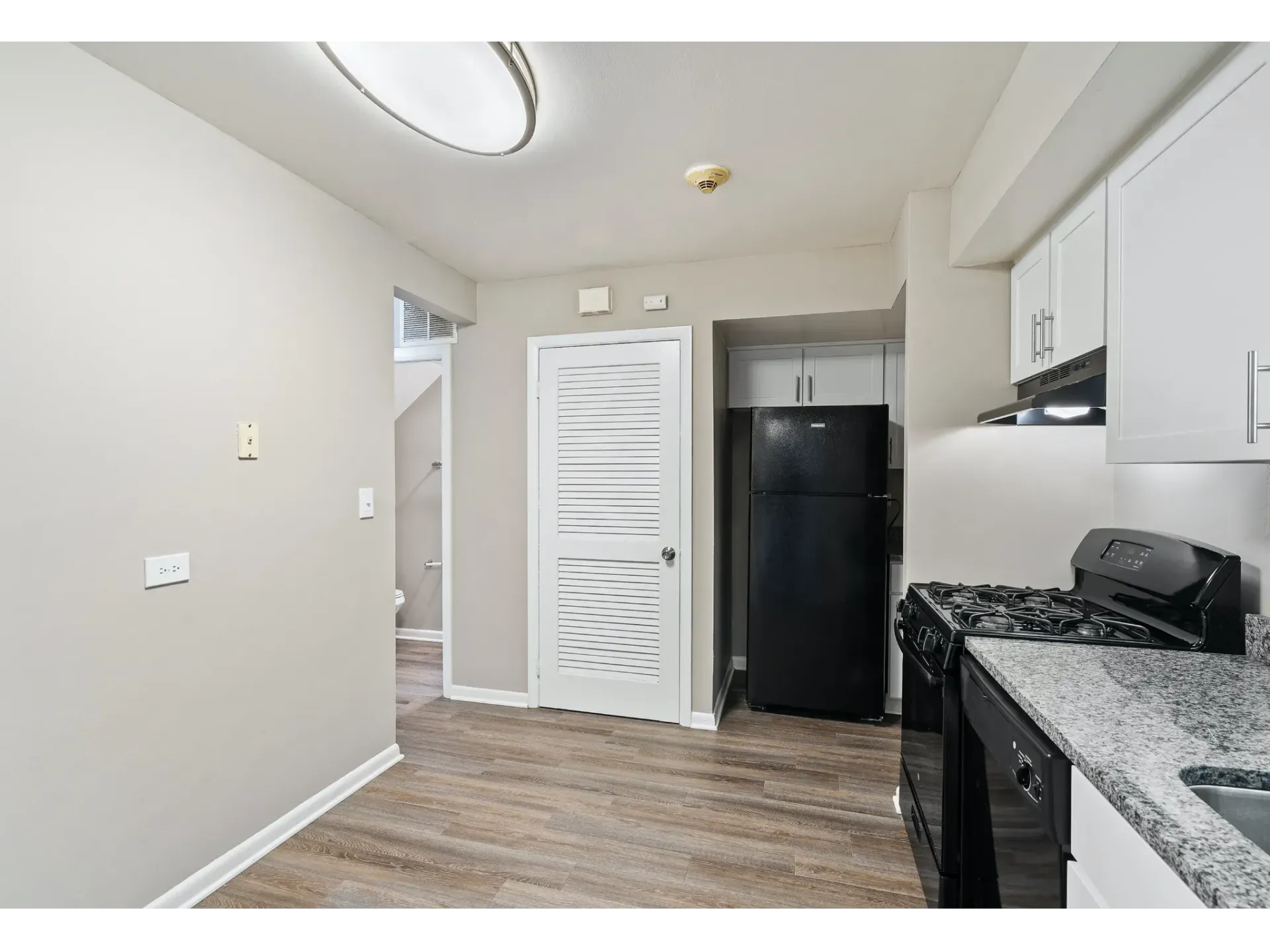 Interior view of a kitchen featuring black appliances and granite countertops.