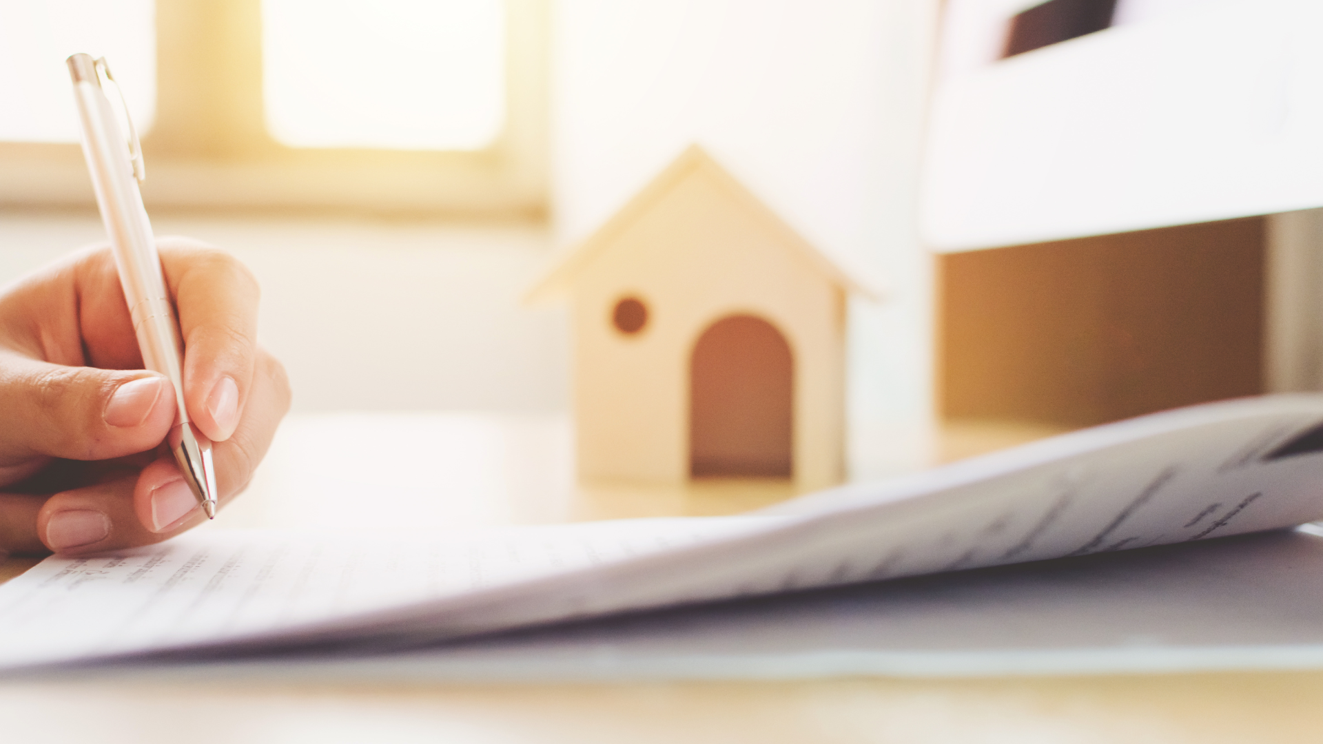 Suburban house with tan siding, brick accents, and a green lawn under a bright blue sky.