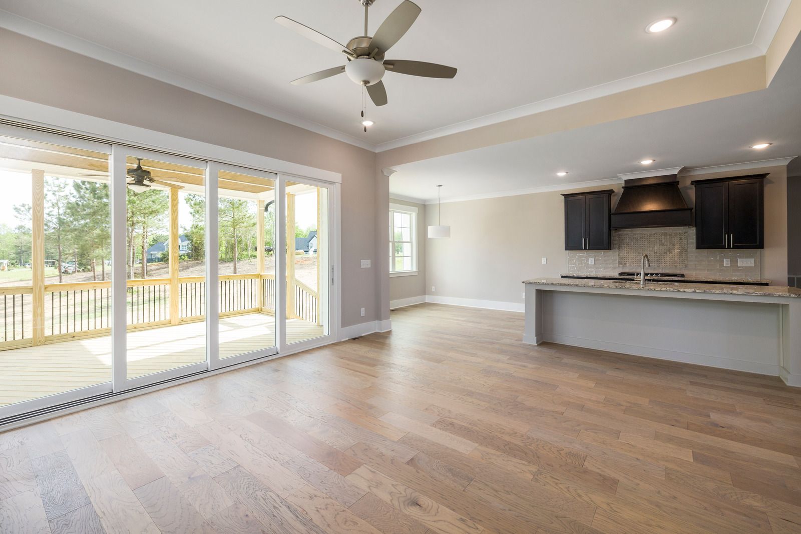 Spacious, light-filled interior with wood flooring, kitchen with island, and sliding glass doors to deck.