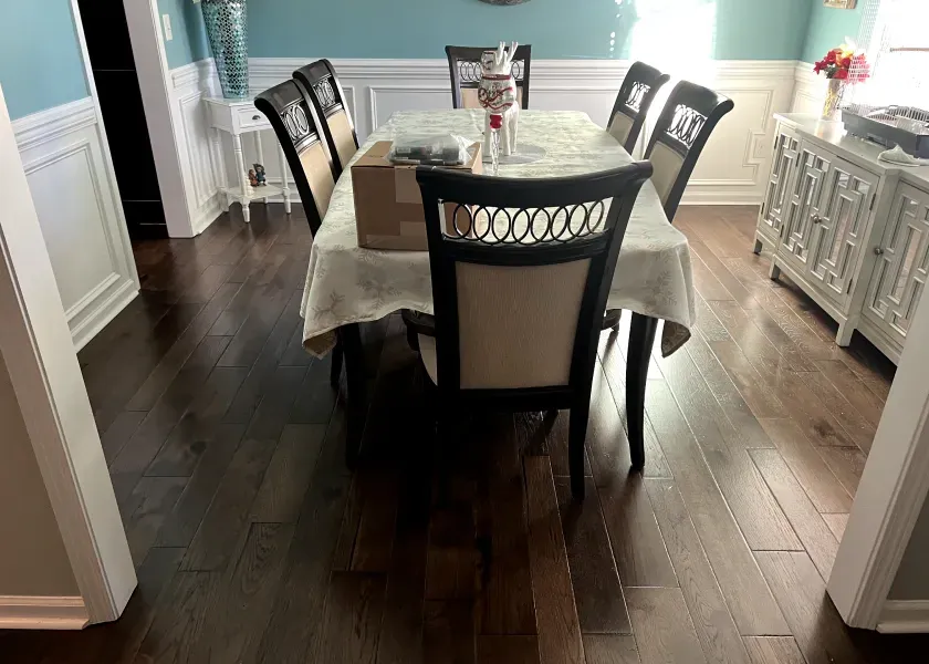 Dark wooden dining room with a table set for six, a box on the table, and a decorative white cabinet.