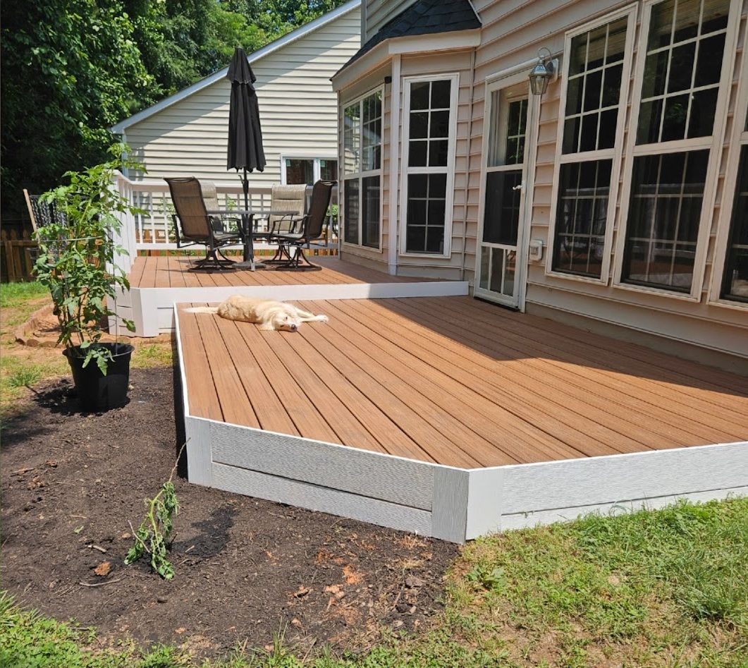 A brown composite deck with white trim extends from a house; a dog rests on it.