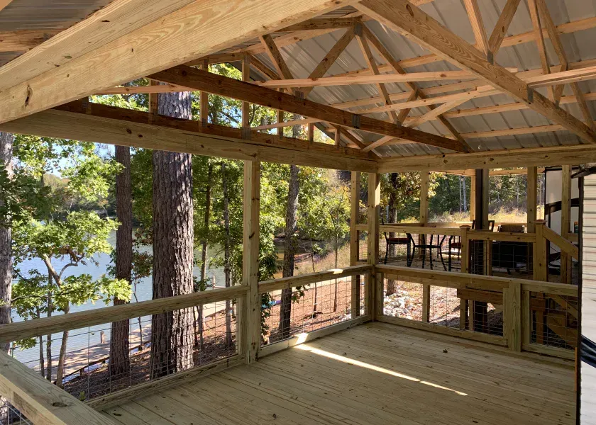 Wooden screened porch with a view of trees and water.