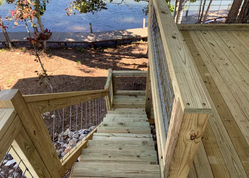 Wooden stairs leading down from a deck to a waterfront.