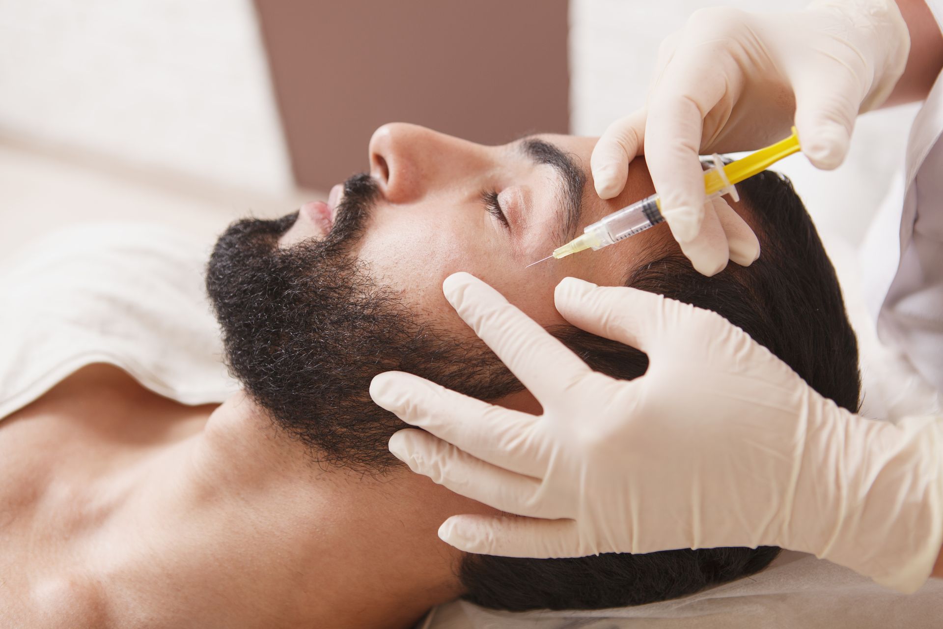 A man with a beard is getting a botox injection in his face.