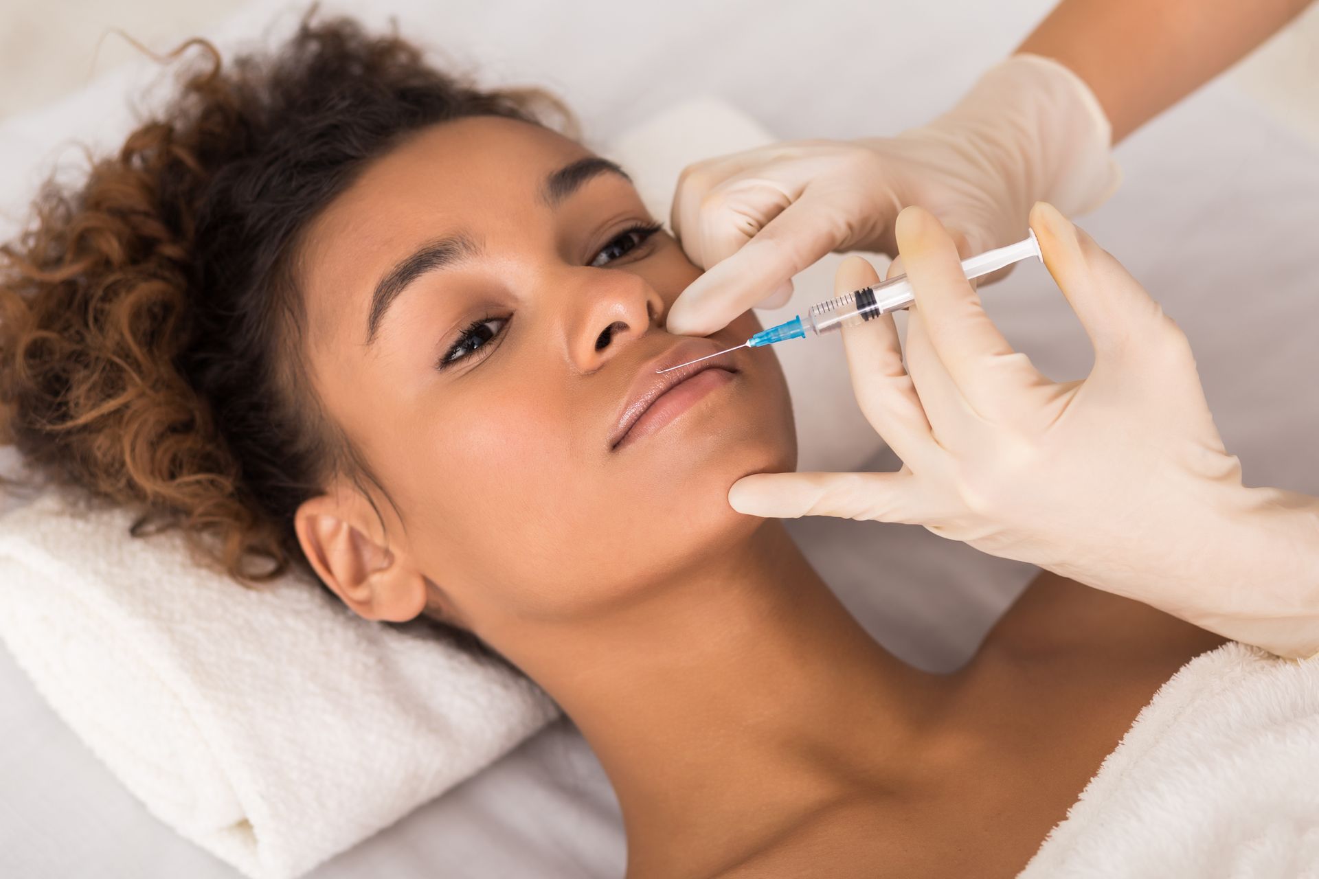 A woman is getting a botox injection in her lips.