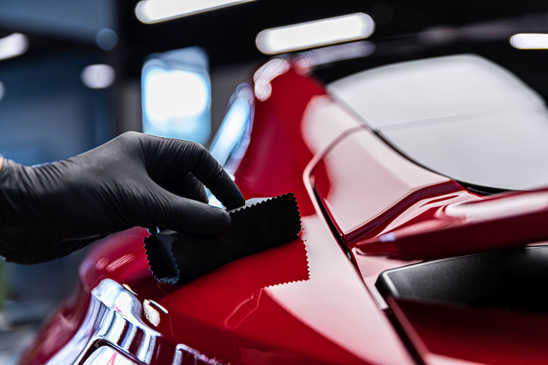 Gloved hand adding ceramic paint protection to a red car’s body with a cloth in Yucaipa, CA