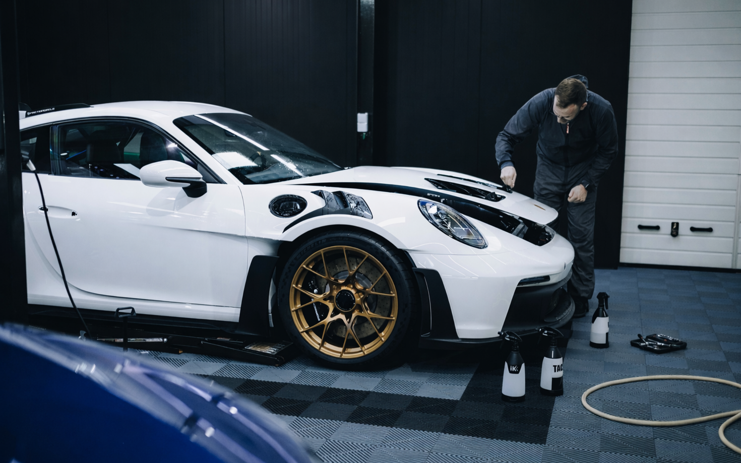 White sports car with gold rims getting windows tinted at $99 Tint Club in Yucaipa, CA near Calimesa, CA  by a person in a garage
