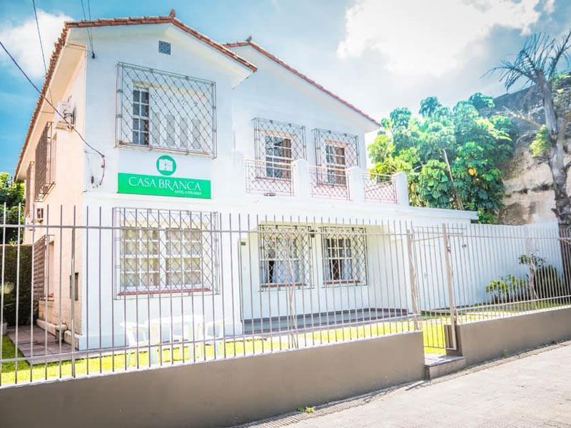 Um prédio branco de dois andares com uma placa verde escrito 