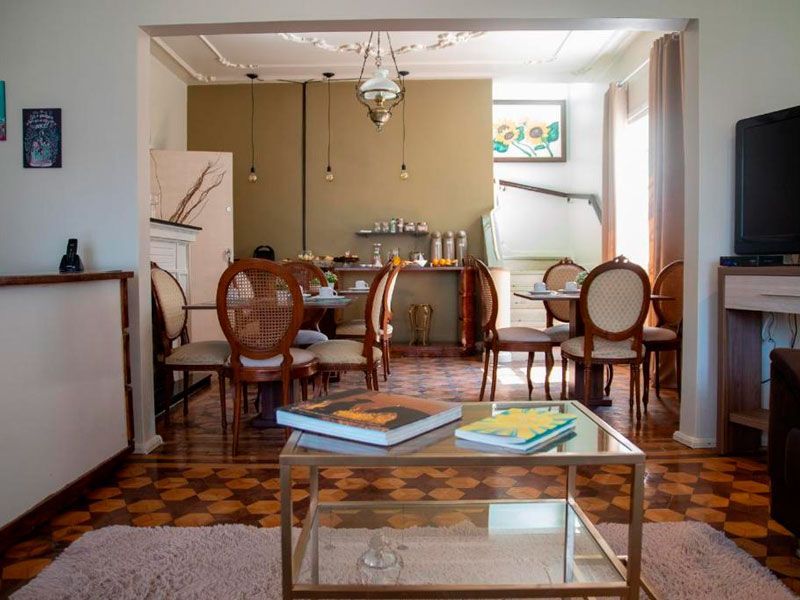 Sala de estar e jantar com uma mesa de centro de vidro em primeiro plano, piso de madeira e uma mesa de jantar ao fundo.