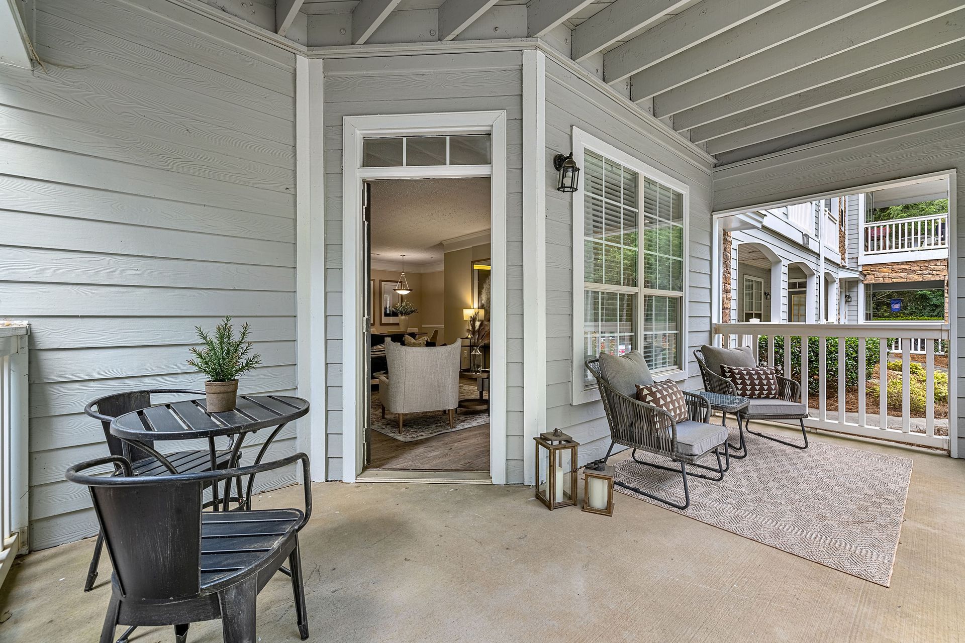 Outdoor porch with seating, table, and an open door to a living room at Marquis at Sugarloaf, offers Duluth apartments for rent.