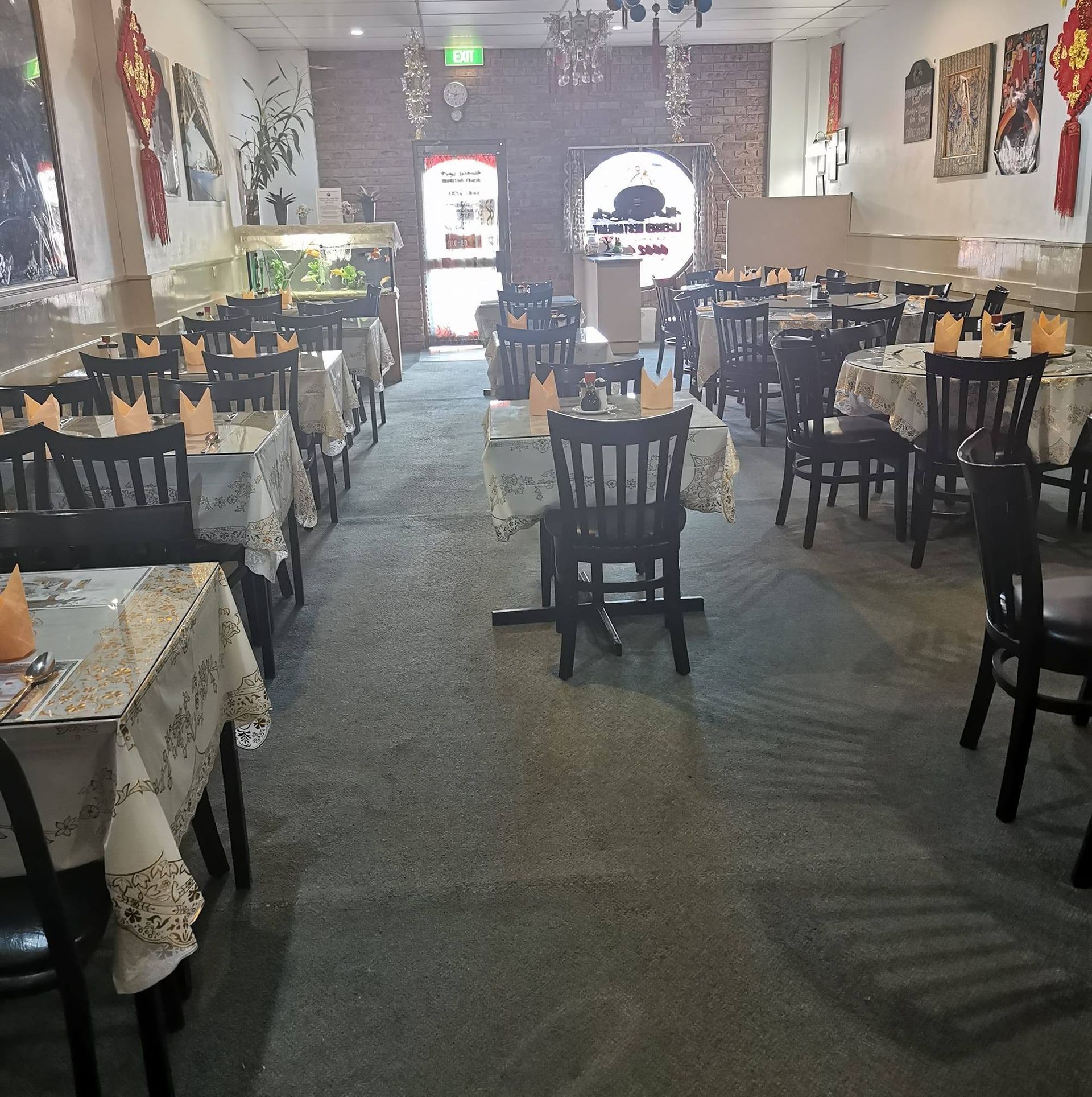 Dining area in a restaurant with multiple tables covered in white cloths, black chairs, and festive hanging decorations.