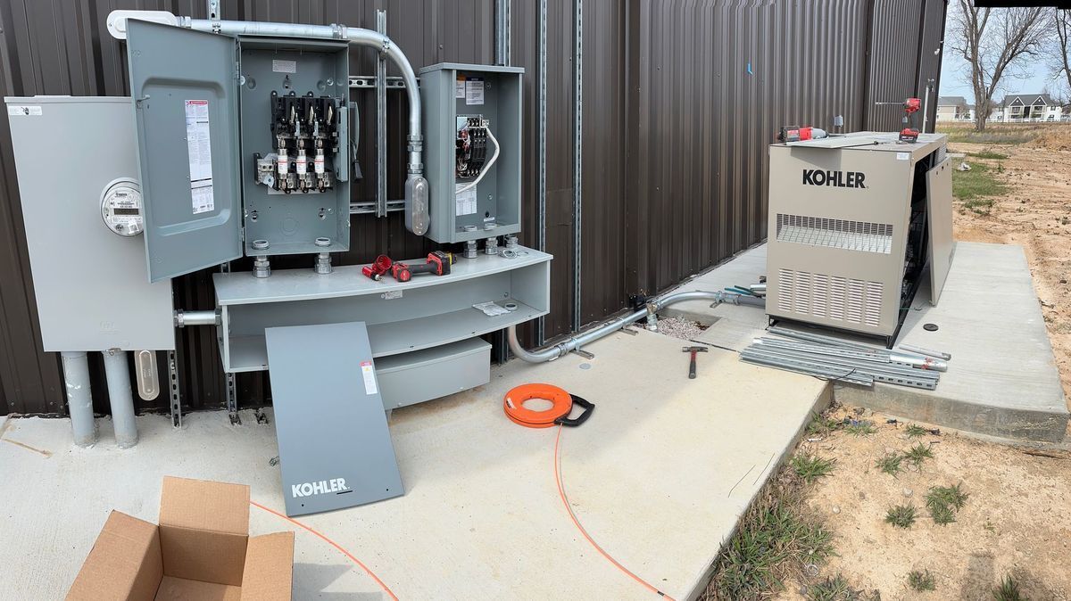 Electrical panel installation next to a building, with a generator nearby.