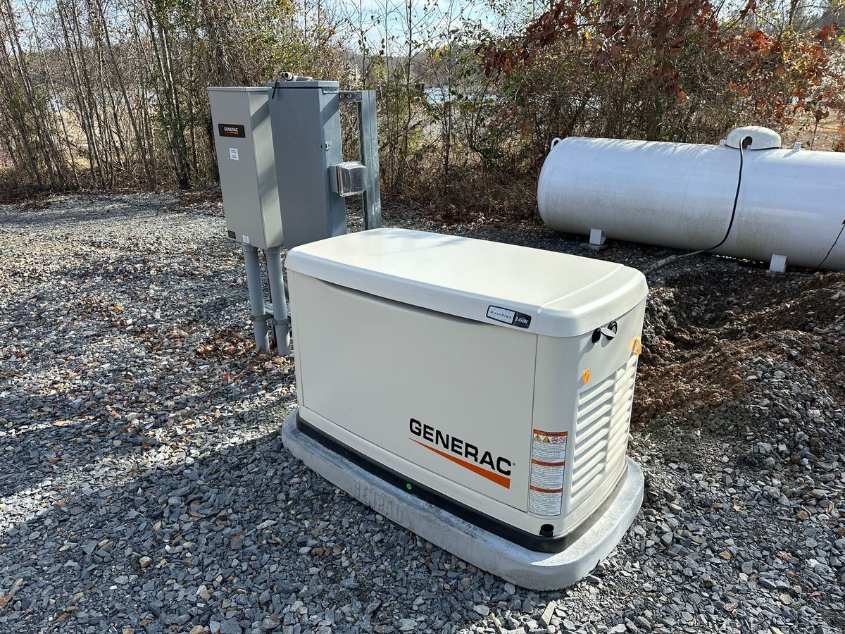 Generac generator on gravel with electrical box and propane tank outdoors.