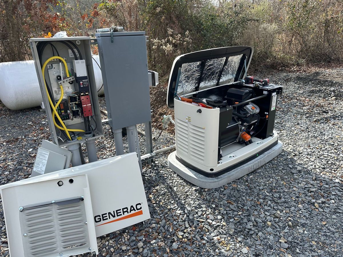 A Generac home generator with open panels, gray control box, set on gravel outdoors.