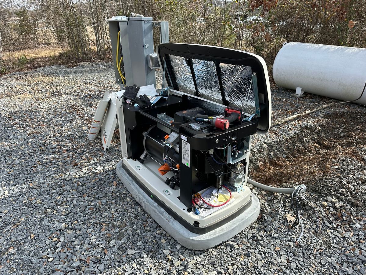 Generator with open access panel on gravel. Exterior setting with a white tank in the background.