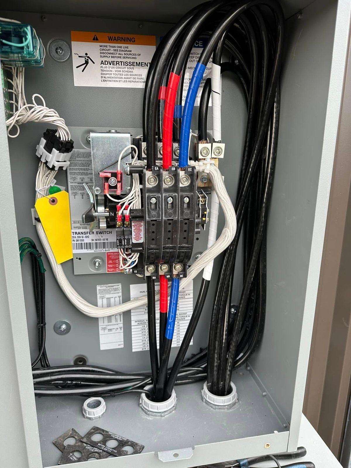 Electrical panel with connected wires, breakers, and labels inside a metal box.