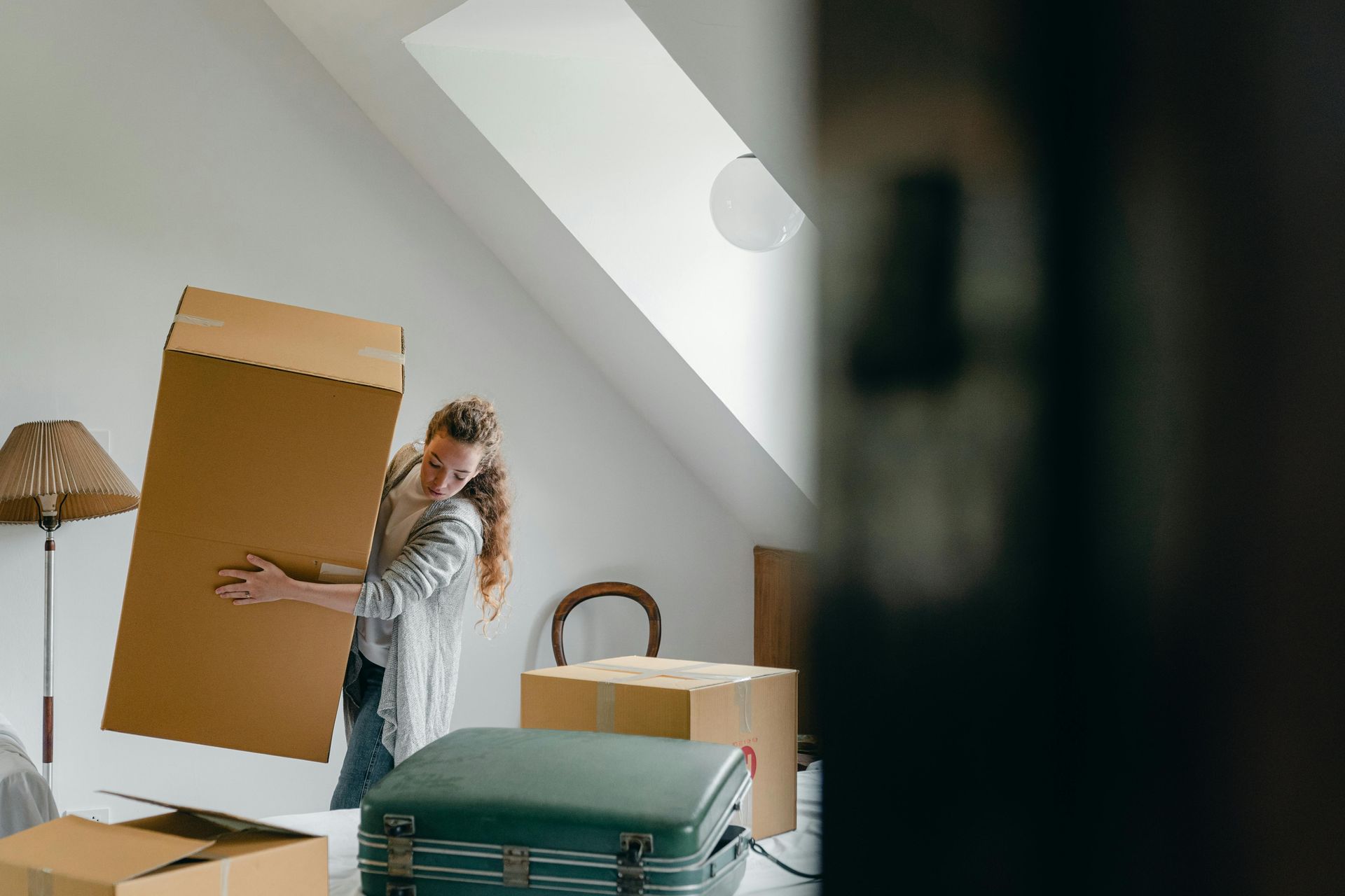 A woman is carrying a cardboard box in a room.