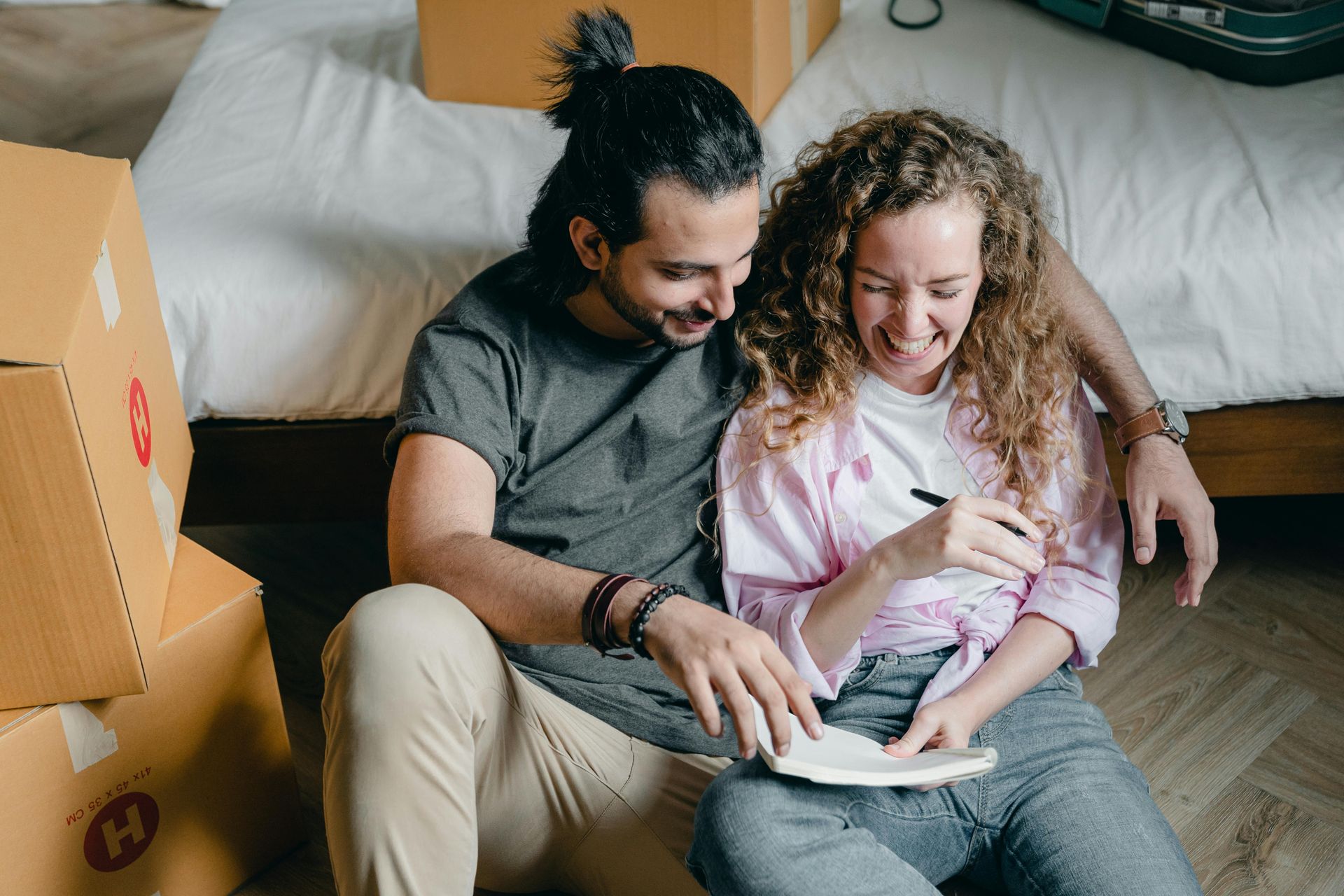A man and a woman are sitting on the floor looking at a tablet.