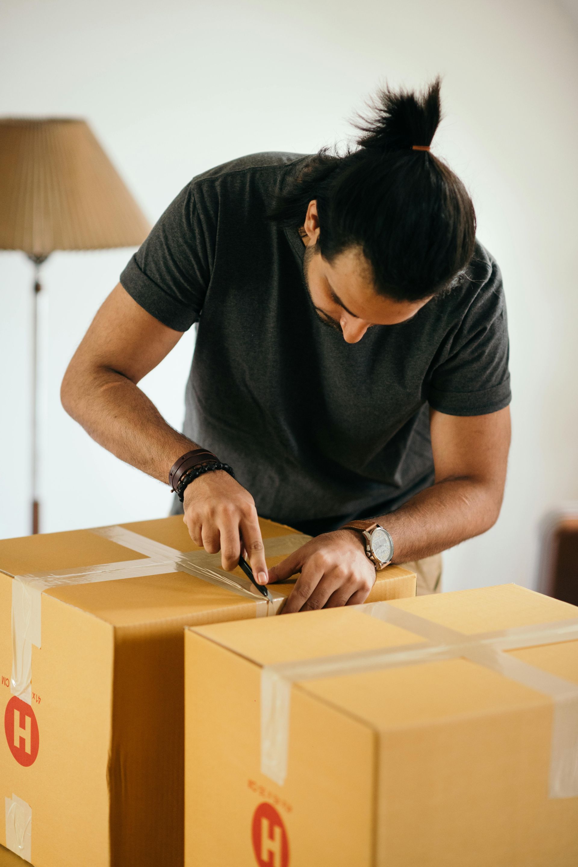 A man is wrapping a cardboard box with tape.
