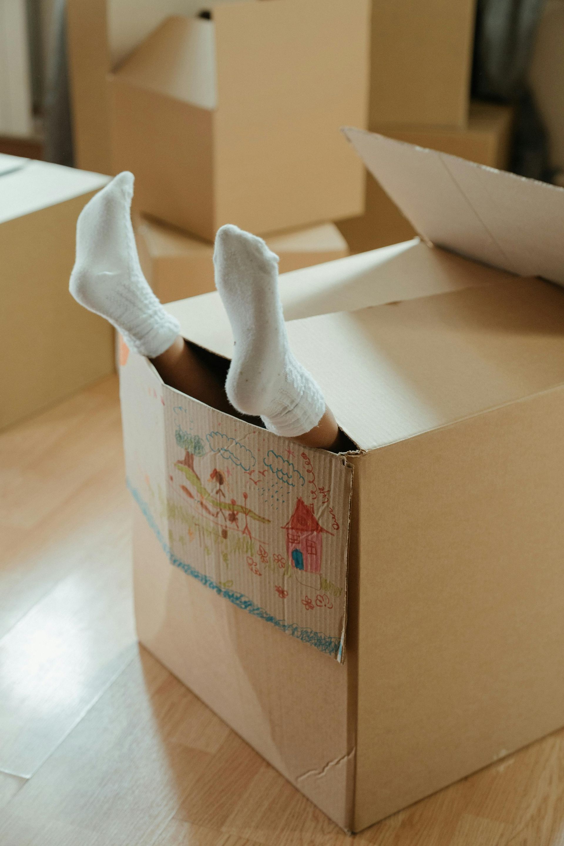 A person is sticking their feet out of a cardboard box.