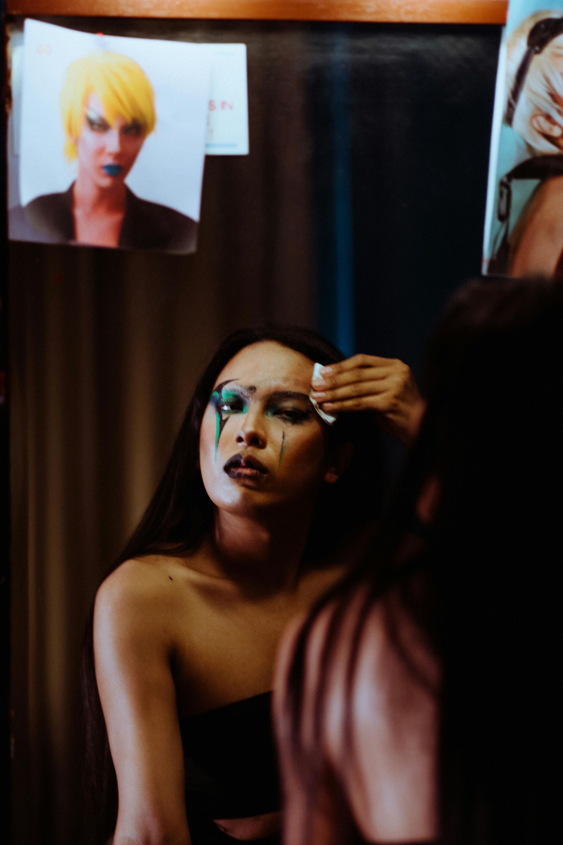 A woman is getting her makeup done in front of a mirror.