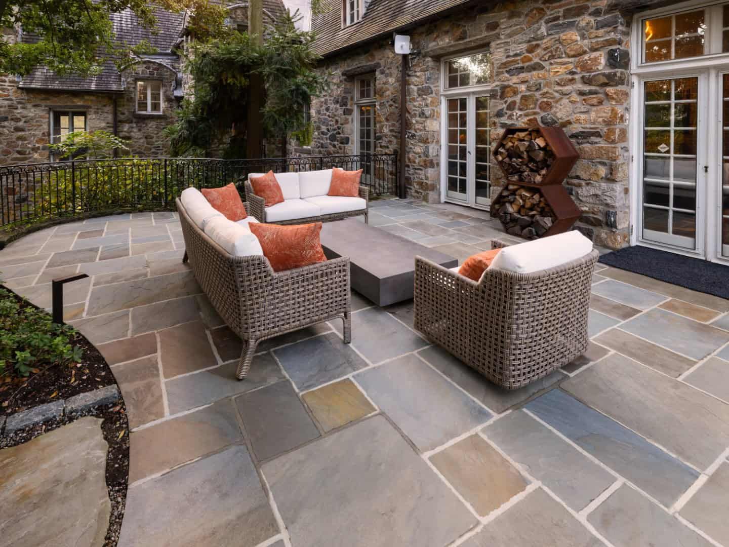 Patio with wicker furniture, stone floor, and stone building.
