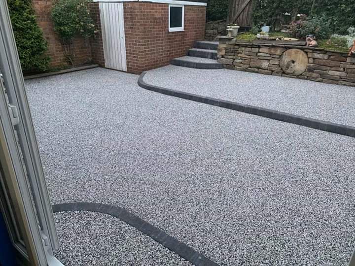Grey gravel driveway with a brick building and steps.