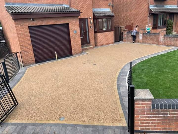 Stone patio leading toward a manicured lawn with hedges and bushes.